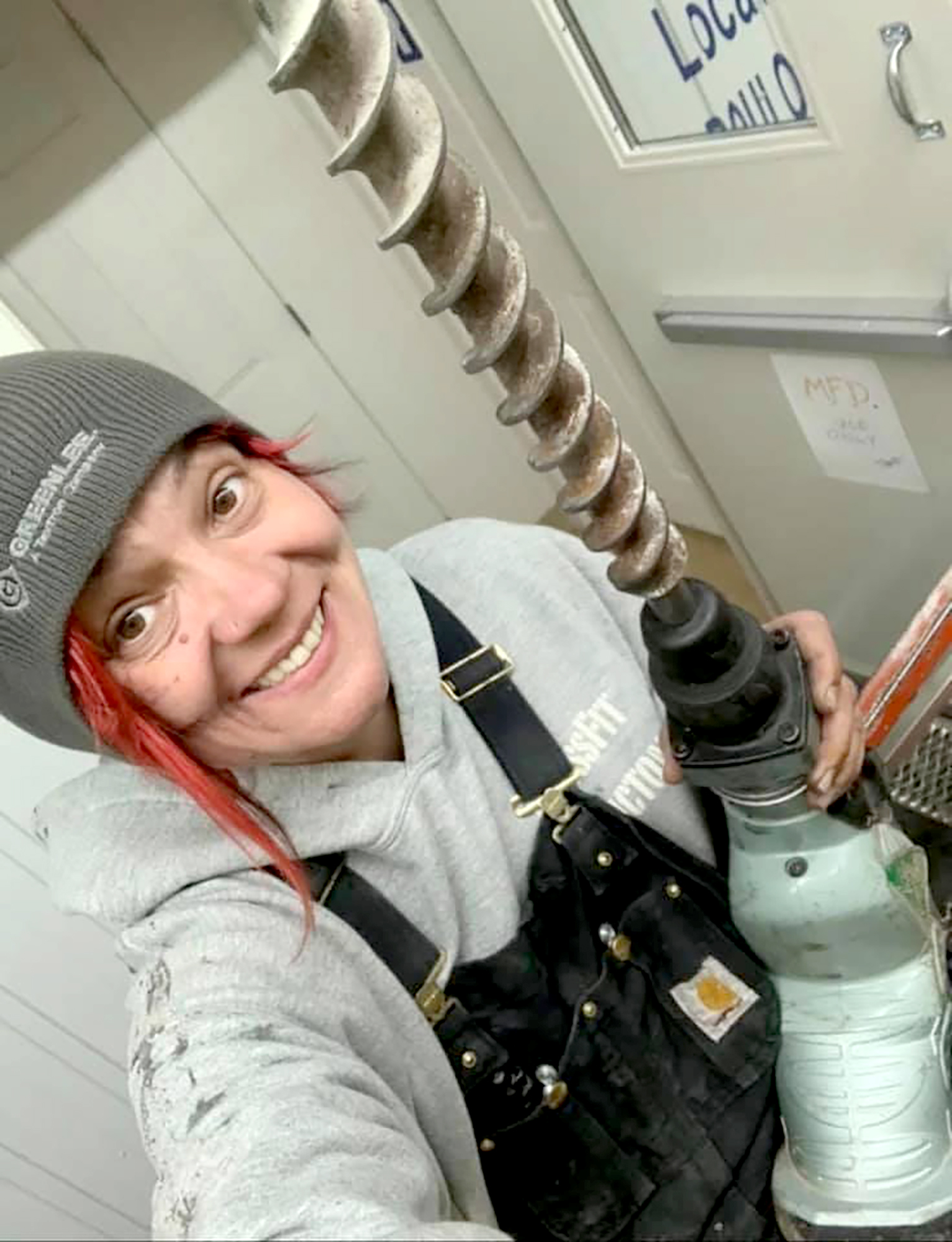 TIna Young holding a large tool grinning at the camera - power emergencies, renovations